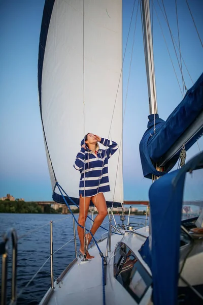 Güzel kız gün batımında bir yatta dinleniyor.