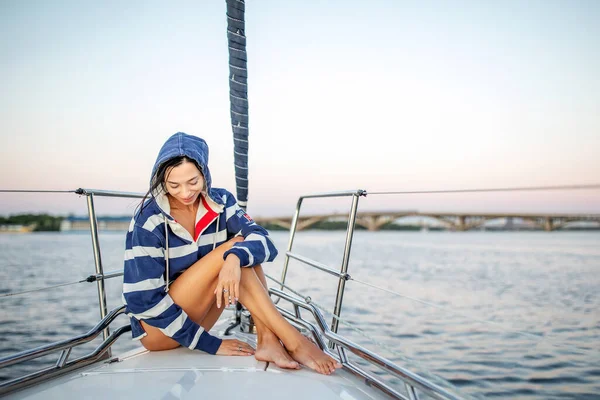 美しい女の子は日没時にヨットで休んでいます ロイヤリティフリーのストック画像