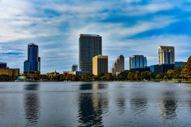 Orlando, Florida. 24 Aralık 2018. Renkli binalar sonbahar orman, göl Eola Park ve gökkuşağı renkleri amfitiyatro güzel günbatımı arka planda Orlando Downtown area (2).