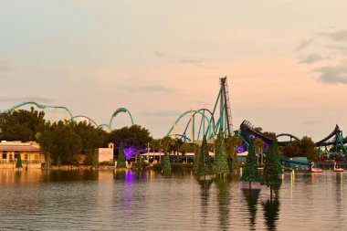 Orlando, Florida; 21 Kasım 2018. Noel ağacı üzerinde göl ve güzel günbatımı arka plan International Drive alanı üzerinde renkli rollercoaster