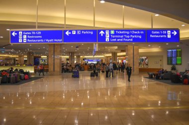 Orlando, Florida 'da. 01 Mart 2019. İnsanlar yürüyor, ve bagagges ile dinleniyor. Orlando Uluslararası Havaalanı 'nda Gates, otopark, Bilet ve check-in işareti.