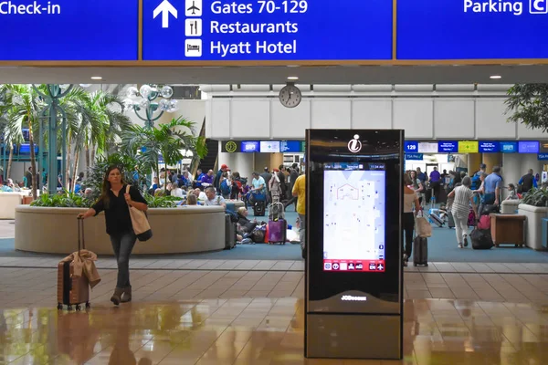 佛罗里达州奥兰多2019年3月1日携带手提箱行走的妇女 游客中心屏幕和奥兰多国际机场办理登机手续的蓝色标志的顶视图 — 图库照片