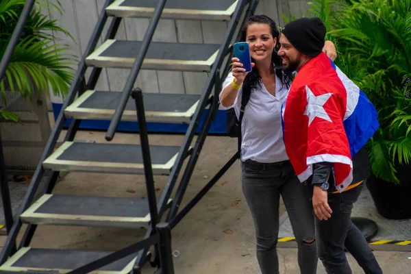 Orlando, Florida. March 17, 2019. Couple of Cubans, wearing a flag, take a selfie in recital of Gente de Zona at Seaworld in International Drive Area. — Stock Image Orlando Florida March 2019 Couple Cubans Wearing Flag Take Selfie Stock Picture