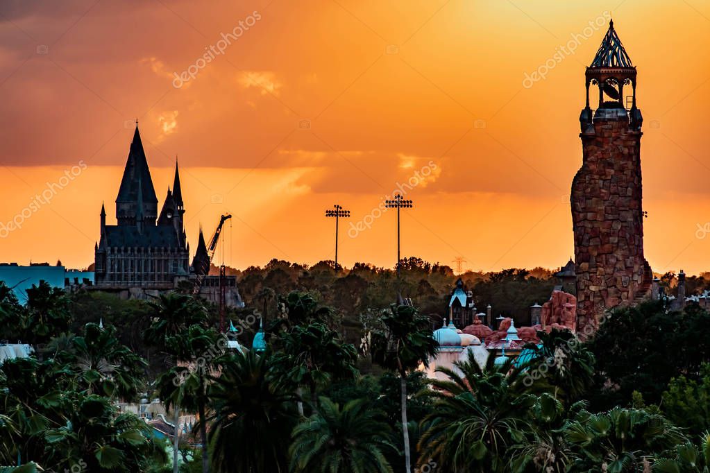Orlando, Florida. April 18, 2019. Top view of Hogwarts Castle and Island of Adventure lighthouse on colorful sunset sky background at Universal Studios area (1)