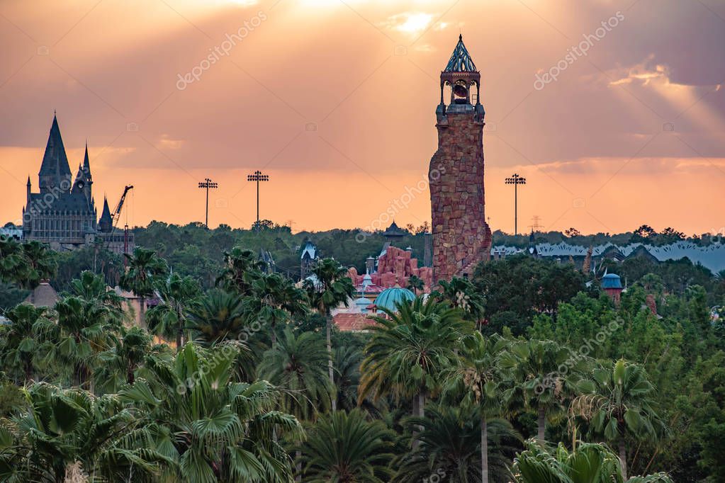 Orlando, Florida. April 18, 2019. Top view of Hogwarts Castle and Island of Adventure lighthouse on colorful sunset sky background at Universal Studios area (3).