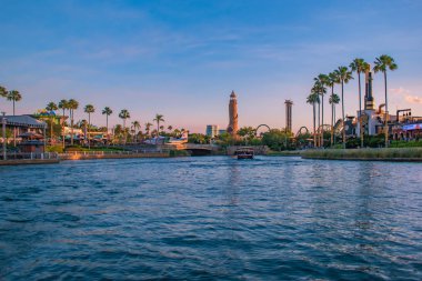 Orlando, Florida. 21 Mayıs 2019. Universal Studios alanında palmiye, uçak, tekne ve Adventure Island deniz feneri ile City Walk iskelesi manzara yaz günbatımı görünümü (3).