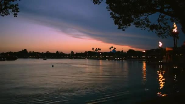 フロリダ州オーランド2019年5月28日ウォルト ディズニー ワールド リゾートのエプコットの美しい夕日に湖で航海する巨大なトーチとセキュリティボートとドックサイドのパノラマビューの時間経過 — ストック動画