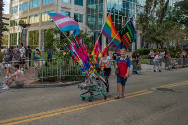 Orlando, Florida. 12 Ekim 2019. Eola Gölü bölgesinde gökkuşağı ve transseksüel bayrakları satan anne ve kız (215)).