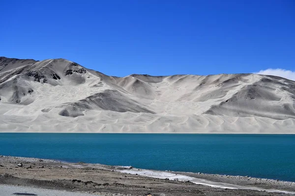 Wydmy i turkusowy niebieski woda nad jeziorem Bulunkou na Karakorum Highway, Xinjiang — Zdjęcie stockowe