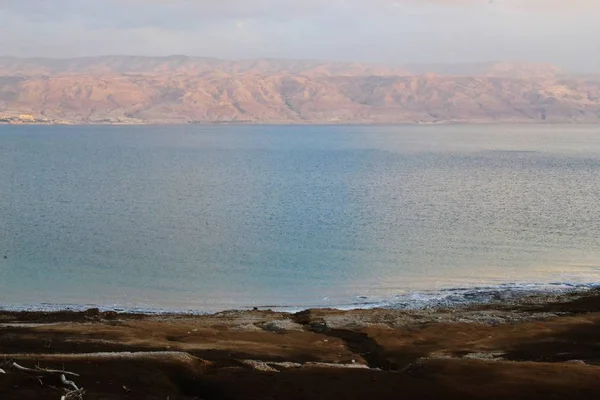 Západ slunce a setmění na pobřeží Mrtvého moře, skály a slané pláž s geologic rock a solných vrstvách, Izrael — Stock fotografie