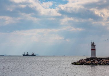 Deniz feneri ve gemi yollarında Boğaz'ın, Türkiye'nin girişinde bulutların arasından güneş ışınlarının aydınlatmak