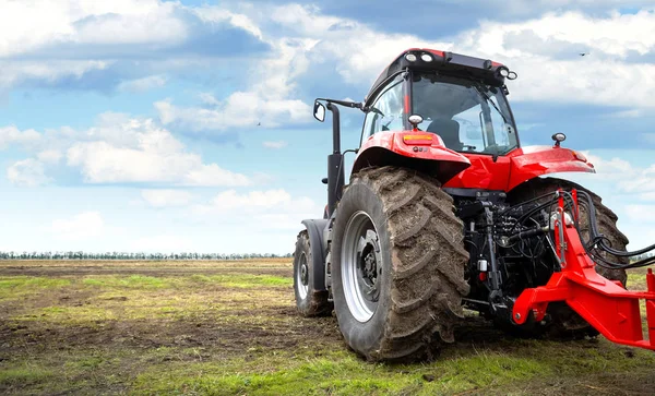Трактор работает в поле против облачного неба — стоковое фото