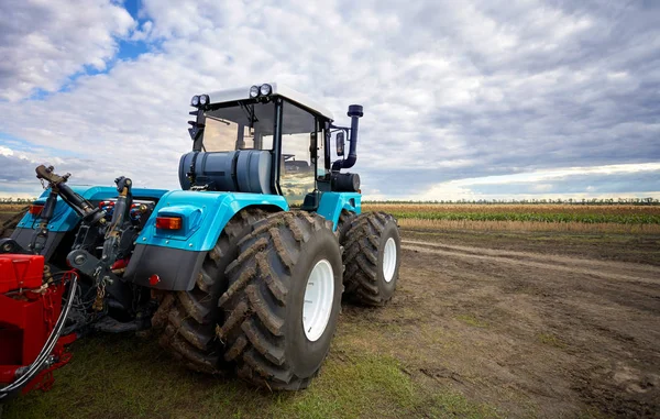 Traktor bekerja di lapangan melawan langit mendung — Stok Foto