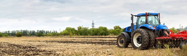 Trattore con aratro funzionante in campo — Foto Stock