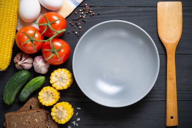 Siyah ahşap zemin taze sebze ile boş gri plaka