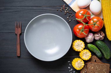 Siyah ahşap zemin taze sebze ile boş gri plaka