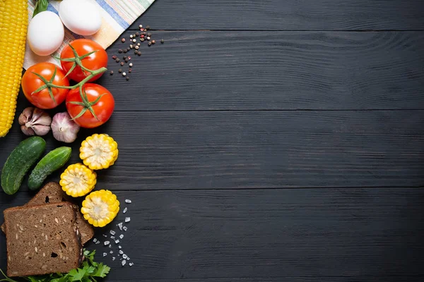 copy space on a black wooden background with lots of fresh vegetables around