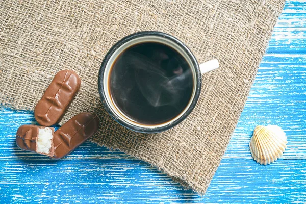 青歳ビレットとチョコレートバーで香り豊かなコーヒーのカップ下から古い布でデザインの木製の背景 — ストック写真