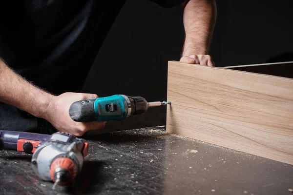 master screwed the scales into wooden furniture, collecting a wooden shelf for the house