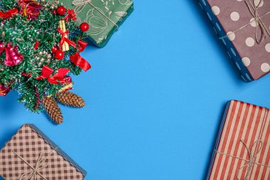 Mavi bir arka plan üzerinde Noel ağacının altında çeşitli ve parlak hediyeler