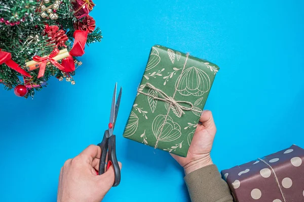 男子用节日套餐中的剪刀打开圣诞礼物 — 图库照片