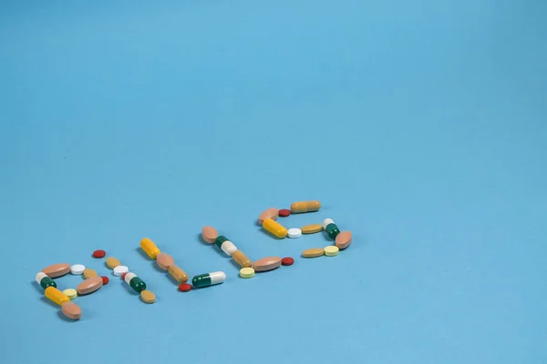 word pills is laid out from colorful pills on a blue background with a place for copy space