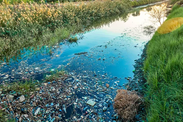 Kanal üzerinden günbatımı çöp ve plastik avuç içi arasında kirli