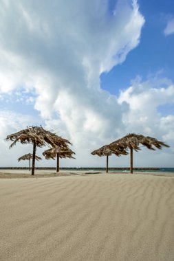 turistlerin dinlenme olmadan Akdeniz kum plajındaki hasır plaj şemsiyeleri