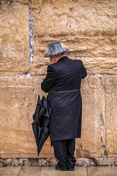 雨の下でレインカバーの大きな黒の帽子で泣いての壁付近に祈っているユダヤ人を信じること — ストック写真