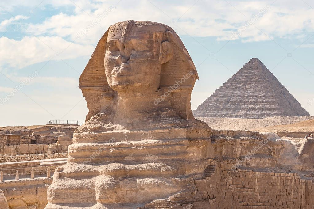 Sphinx monument against the background of large pyramids on a sunny day