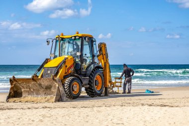15/12/2018 İsrail, Netanya, sürücü Ekskavatör kova manipülatör çalışır, bir Halk Plajı tamiri güneşli bir günde Akdeniz, onun yardımcısı aşağıdaki kıyısında işlemi gerçekleştirir