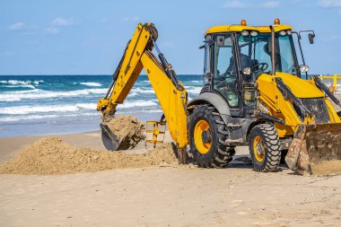 15/12/2018 İsrail, Netanya, sürücü Ekskavatör manipülatör bir kova çalışır, bir Halk Plajı tamiri güneşli bir günde Akdeniz kıyısında gerçekleştirir.