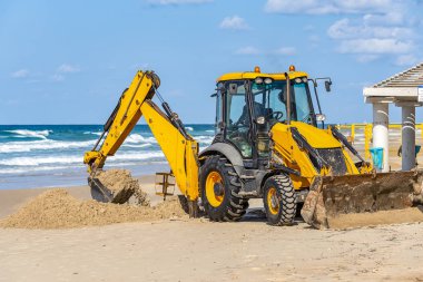15/12/2018 İsrail, Netanya, sürücü Ekskavatör manipülatör bir kova çalışır, bir Halk Plajı tamiri güneşli bir günde Akdeniz kıyısında gerçekleştirir.