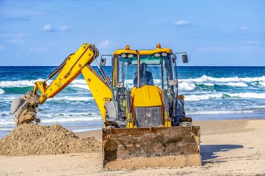 15/12/2018 İsrail, Netanya, sürücü Ekskavatör manipülatör bir kova çalışır, bir Halk Plajı tamiri güneşli bir günde Akdeniz kıyısında gerçekleştirir.