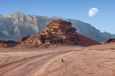 Kırmızı kum Dune ve yol üzerinde görünümü, büyük ay yukarıda ile Ürdün çölünde Wadi Rum inanılmaz ay manzara gider. Wadi Rum, ay Vadisi olarak da bilinir, Ürdün-görüntü