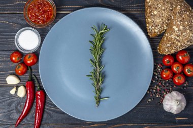 baharat ve sebze çeşitli ve kopya alanı için bir yer ile ahşap bir arka plan üzerinde biberiye ile boş gri plaka