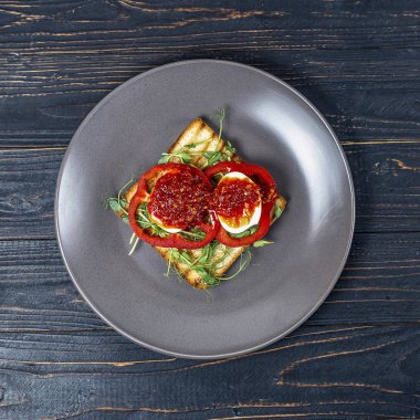 siyah ahşap arka plan üzerinde gri bir tabak üzerinde kavrulmuş tost üzerinde taze sebze ve haşlanmış yumurta ile sandviç