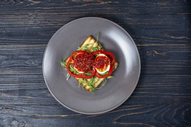 siyah ahşap arka plan üzerinde gri bir tabak üzerinde kavrulmuş tost üzerinde taze sebze ve haşlanmış yumurta ile sandviç