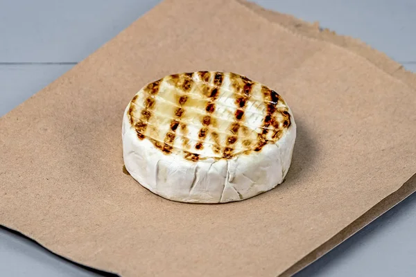 Roasted Camembert on Parchment and Gray Wooden Background with a Place for copy space
