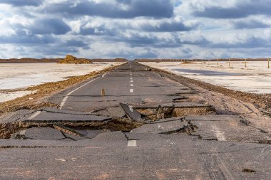 broken asphalt road with cloudy sky in the middle of the  Lut desert,hottest desert in the world, also known like Kalut Desert clipart