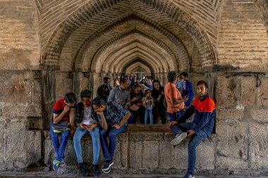 22 / 05 / 2019 İsfahan, İran, insanlar Khaju Köprüsü 'nün altındaki kemerlerde oturup dinleniyorlar, Zayandeh nehri boyunca Khaju Köprüsü' nün gölgesinde üşüyorlar.