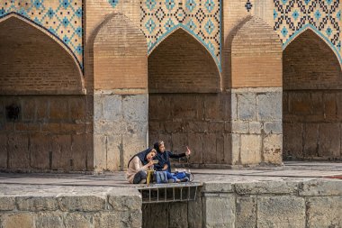 22/05/2019 İran'ın İsfahan kentinde iki İranlı kız, Zayandeh nehri üzerinde bol kemerli Khaju Köprüsü'nde oturuyor ve akıllı telefonda selfie çekiyor 