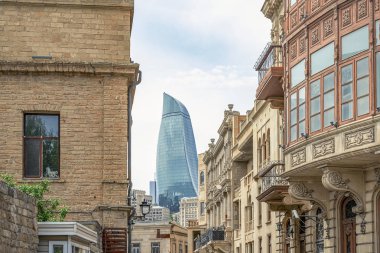 Bakü'nün Icherisheher eski kentinin dar sokaklarından sokak manzarası, geleneksel ev sonları ve modern Alev kuleleri manzaralı tarihi merkezci