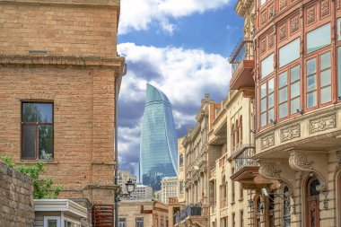 Bakü'nün Icherisheher eski kentinin dar sokaklarından sokak manzarası, geleneksel ev sonları ve modern Alev kuleleri manzaralı tarihi merkezci