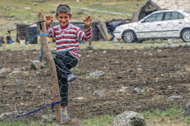 25/05/2019 Bazargan, Batı Azerbaycan Eyaleti, İran, küçük bir Kürt çocuk çit ızgarası üzerinden bir fotoğrafçıya bakıyor
