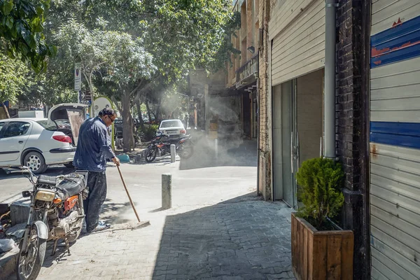 18/05/2019 İran'ın İsfahan vilayetinde İranlı bir adam sabah caddeyi süpürüp toz topluyor