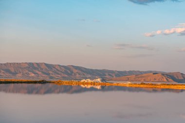 İran'da tuzlu Maharlu Gölü üzerinde su gökyüzü yansıması ile güzel manzara ve gün batımı, Şiraz şehir yakınlarındaki Fars Eyaleti, kan gibi inanılmaz kırmızı su ile