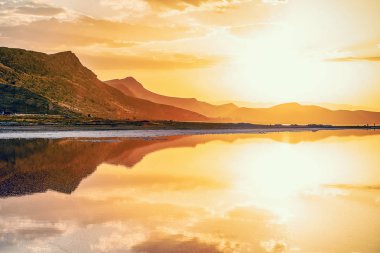 İran'da tuzlu Maharlu Gölü üzerinde gökyüzü yansıması ile güzel manzara ve gün batımı, Şiraz şehir yakınlarındaki Fars Eyaleti, kan gibi inanılmaz kırmızı su ile