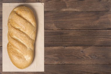 Ahşap zemin üzerinde geri dönüştürülmüş malzemeden yapılmış bir buhar paketindeki klasik ekmek, kağıt torba konsepti ve fotokopi alanı için bir yer.