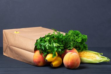 Her çeşit yiyecek ve sebzeyle dolu bir kese kâğıdı ve siyah tahta arka planda meyveler. Geri dönüştürülebilir eko paketleri kavramı